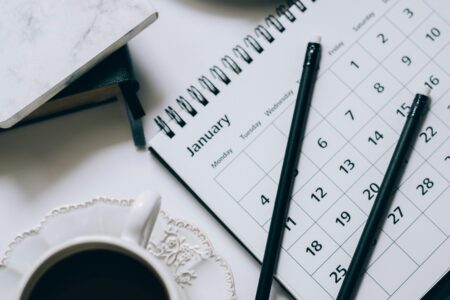 Stylish flat lay of coffee, croissant, and calendar for a productive morning.